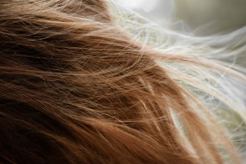 Close-up of neatly styled cornrows on a smiling woman with gold hair cuffs and natural lighting